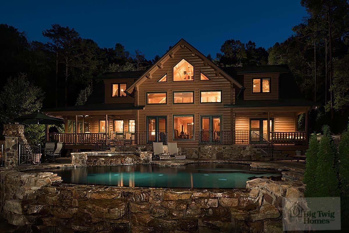 Bennett cedar log home with warm light overlooking a stone terrace