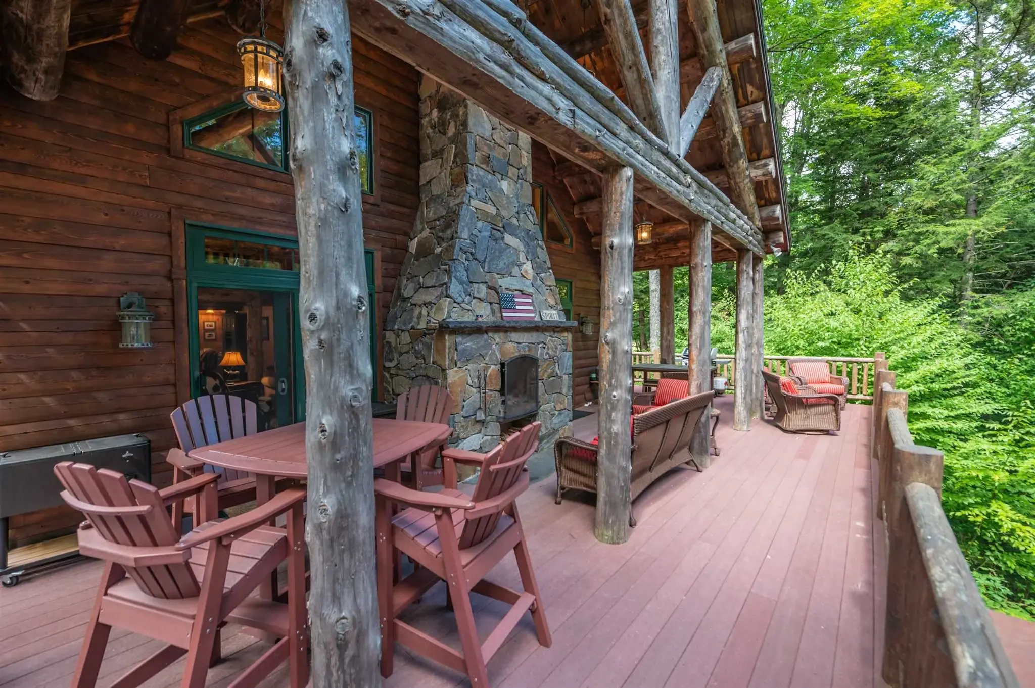 The log posts of the covered porch blend naturally with the surrounding landscape, for a seamless transition from outside to in, while the double-sided fieldstone fireplace is an inviting centerpiece allowing for outdoor living in all kinds of weathe