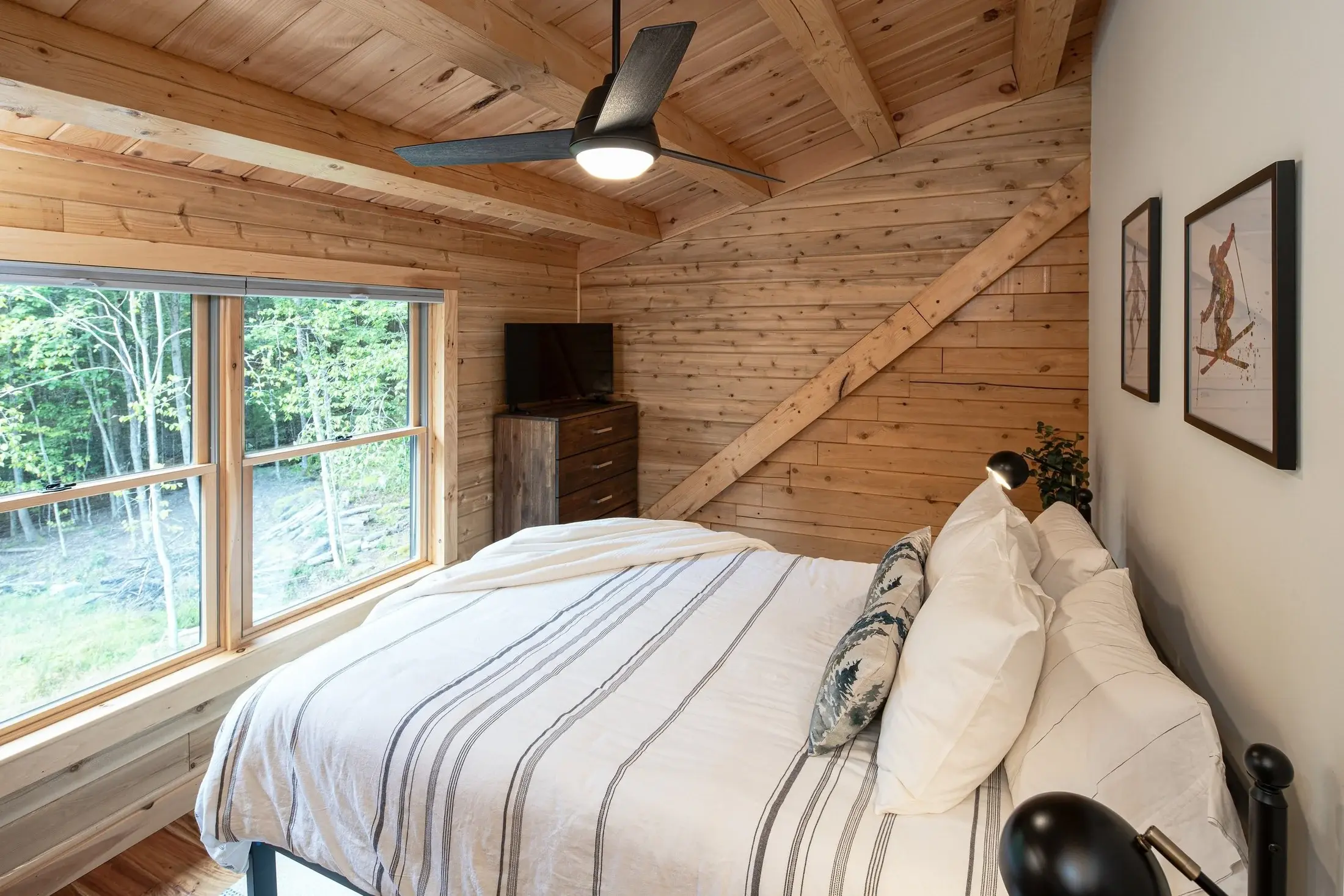 The first of two upstairs bedrooms, this room showcases the architectural beauty of a log home with exposed beams on the walls and ceiling. Incorporating walls with simple drywall is a great way to make a log interior feel more contemporary. 