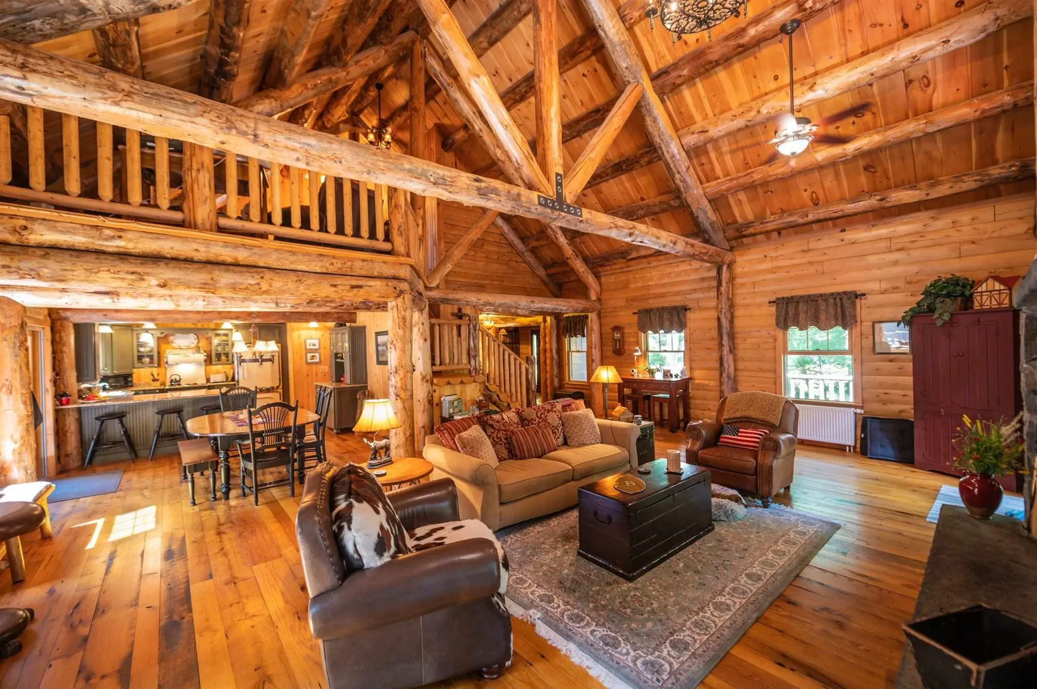 Warm, natural tones of wood pair well with rich brown leather furnishings, keeping the living room cozy and inviting. While open to the dining area and kitchen beyond, the flat ceiling above these spaces helps them feel distinct. 