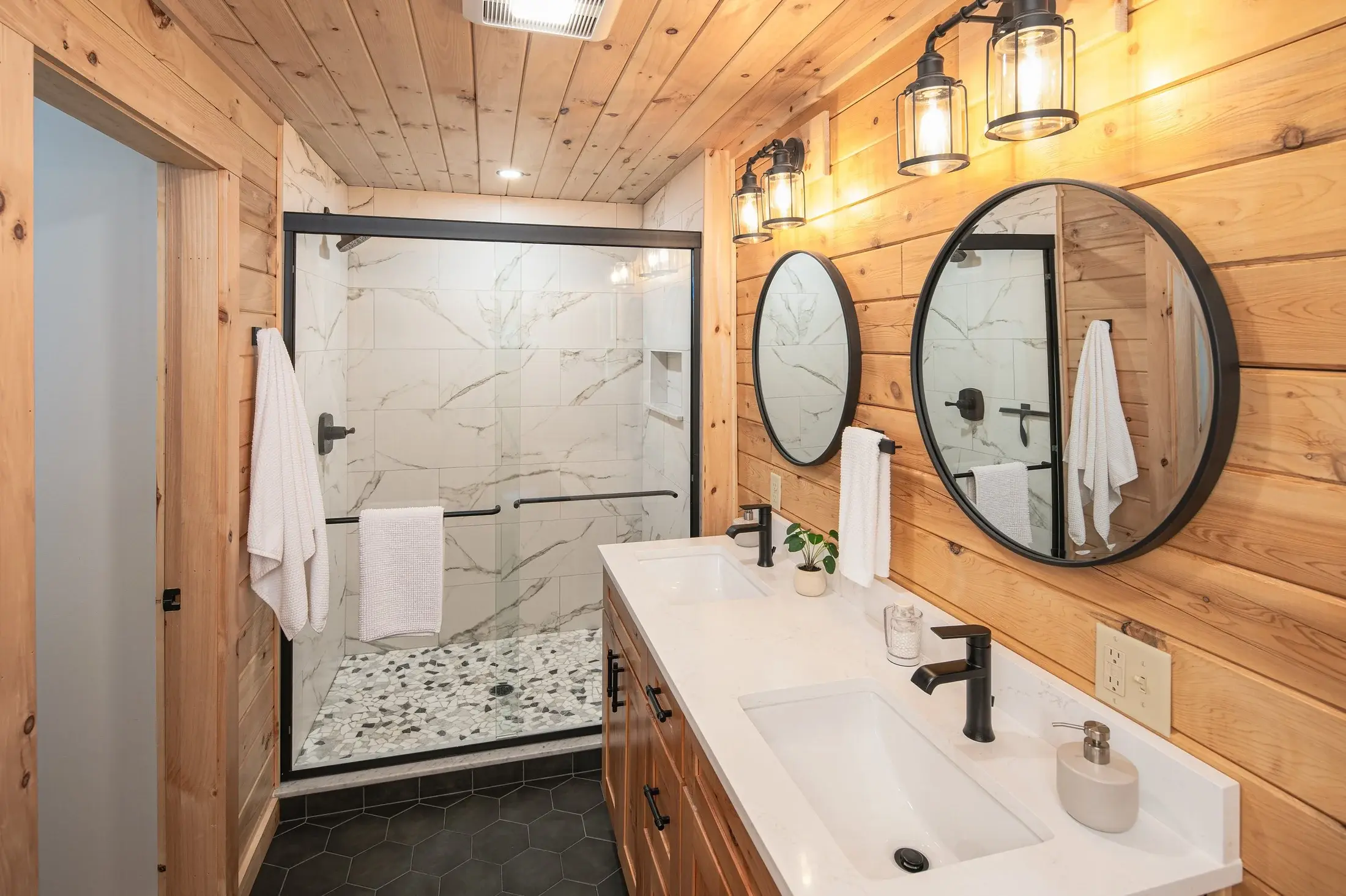 The master bathroom incorporates sleek, modern lines in basic black and white with natural elements like wood and stone for a stylish, balanced design. 