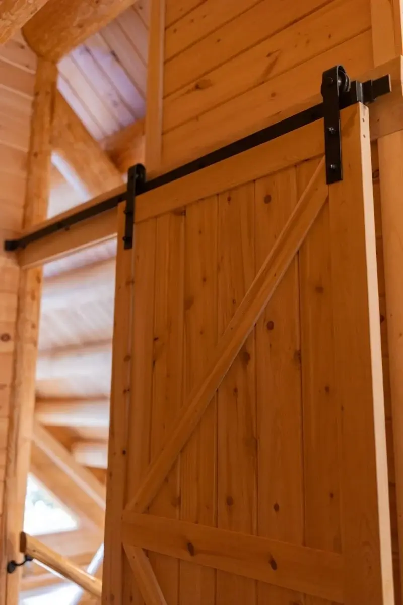 Black metal accents add a contemporary touch to the rustic style of this sliding barn door. 