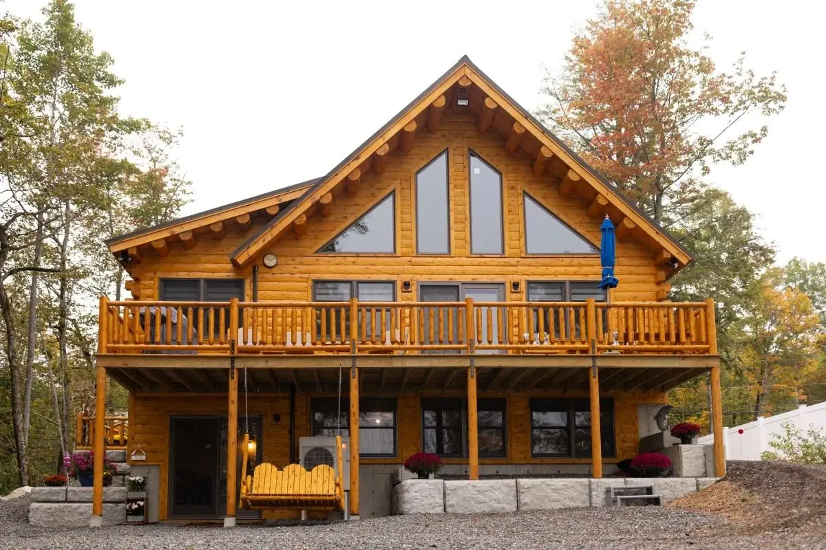 This gorgeous lakehouse is a classic example of log cabin architecture, with its exposed cedar log beams, large front deck, and floor to ceiling windows. 