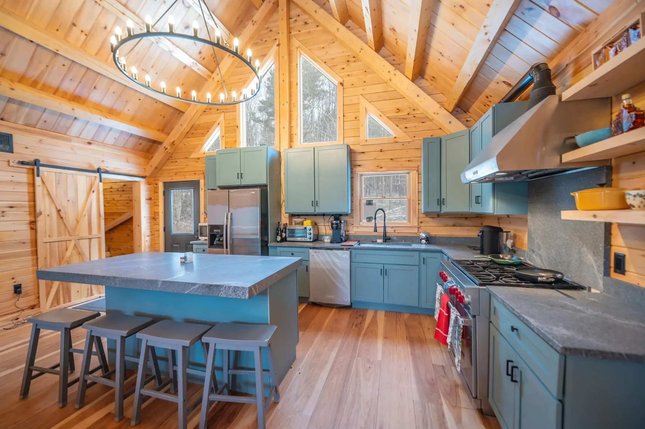 A mix of open shelving and cabinets maximizes storage in this classic L-shaped layout. The island, with its extra thick countertop and square edges, is a substantial, anchoring element- an important consideration in an open concept kitchen. Upper lev