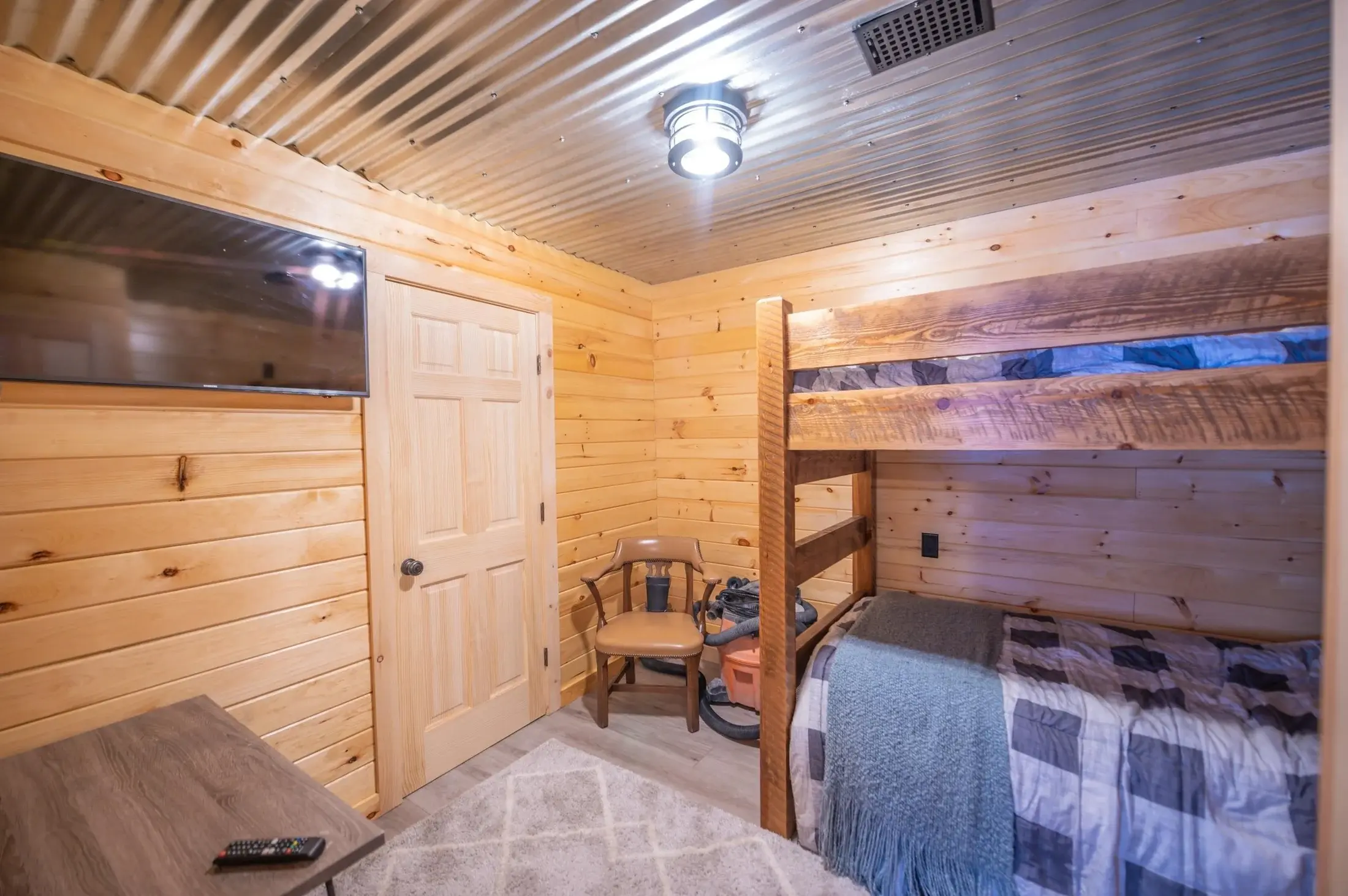 Corrugated metal is a bold choice for a ceiling, but paired with natural wood it feels just right. Just like in the kitchenette it reflects lots of light, making this cozy bunk room feel bright and fun. 