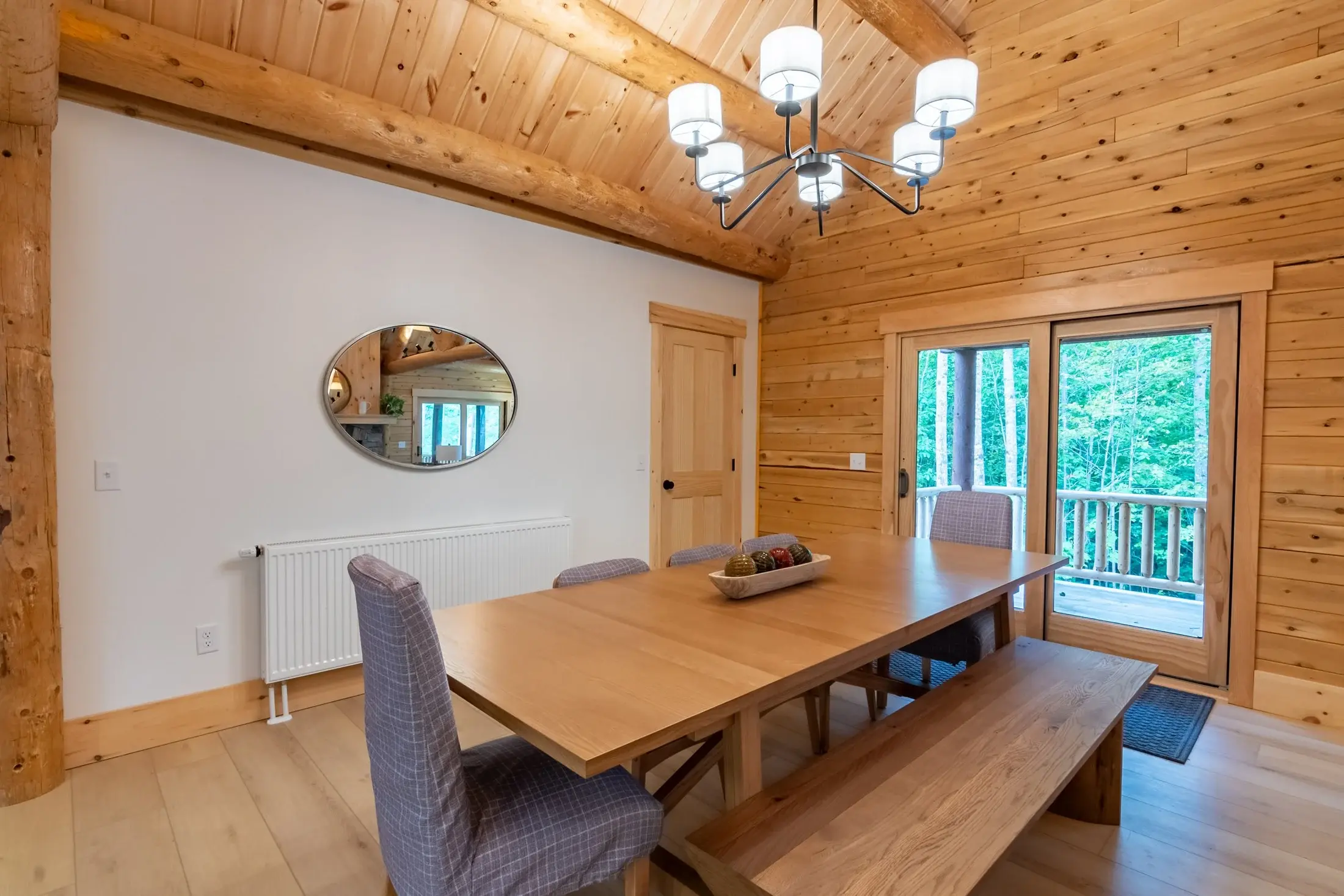A large mirror hung on a white wall adds another layer of light to the dining area. 