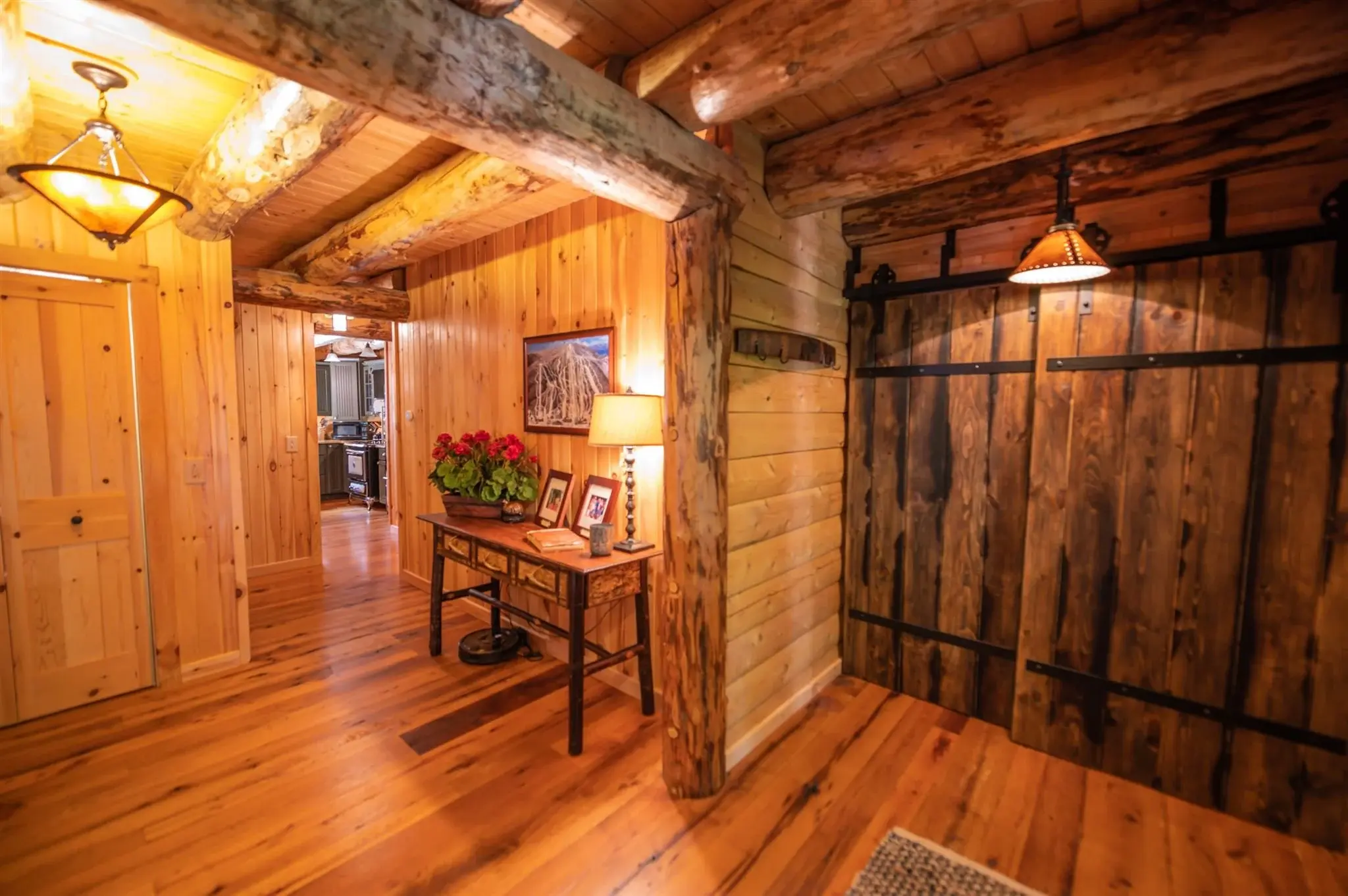 A wide hallway leads to a striking door, adding to the feeling of rustic elegance throughout the home. 