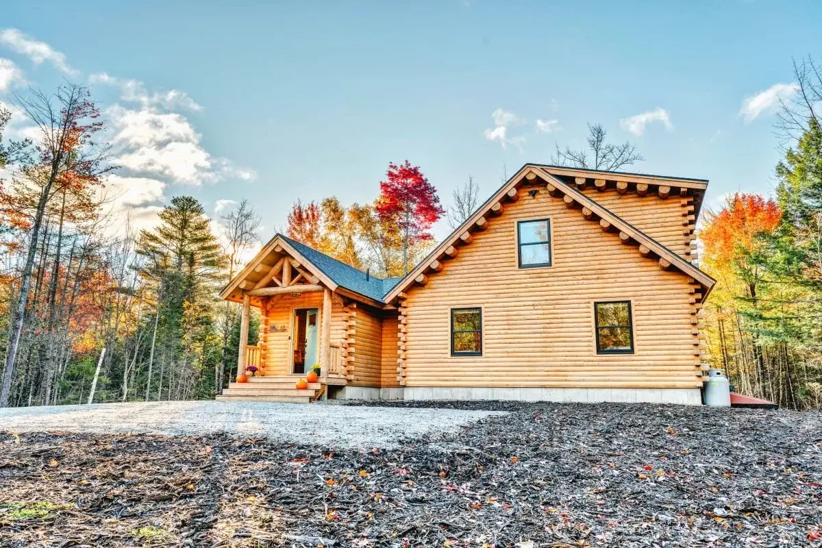 Classic log cabin features like exposed log purlins, square log corners, and well-proportioned roof lines give this home a timeless charm, while the simple black framed windows and dark shingles add modern sophistication. 