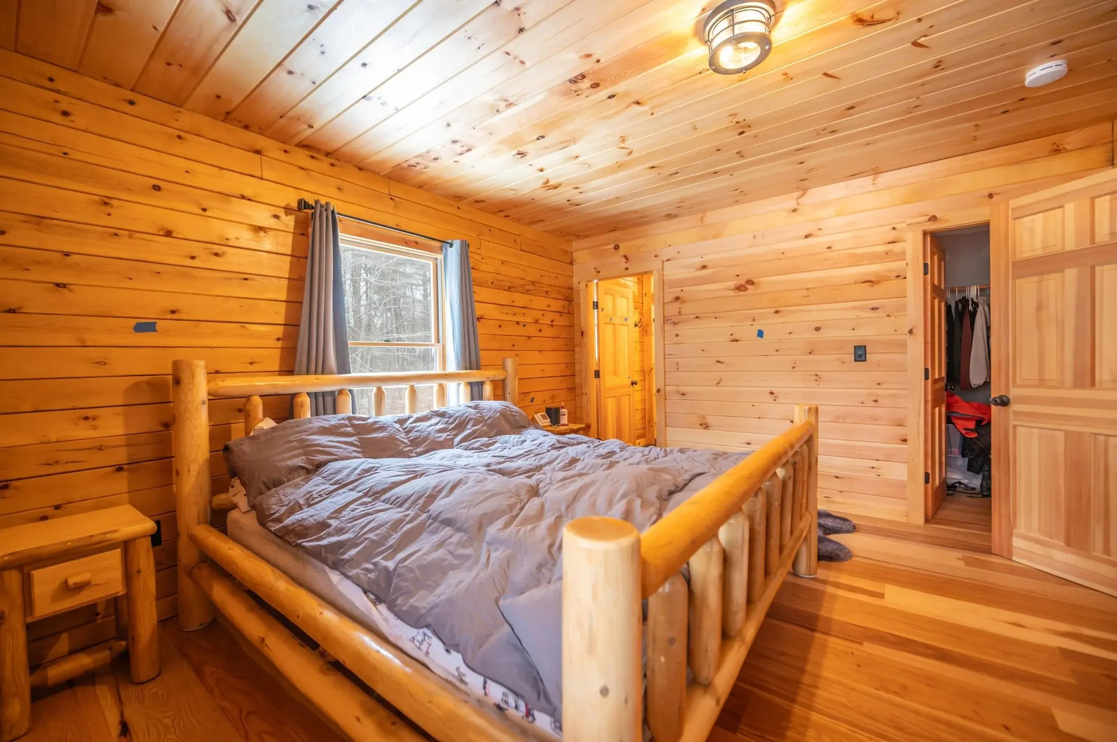 The main floor bedroom is a bold celebration of natural wood- from the walls, floors, and ceiling to the doors and furniture, this room simply glows with the rustic warmth of wood. 