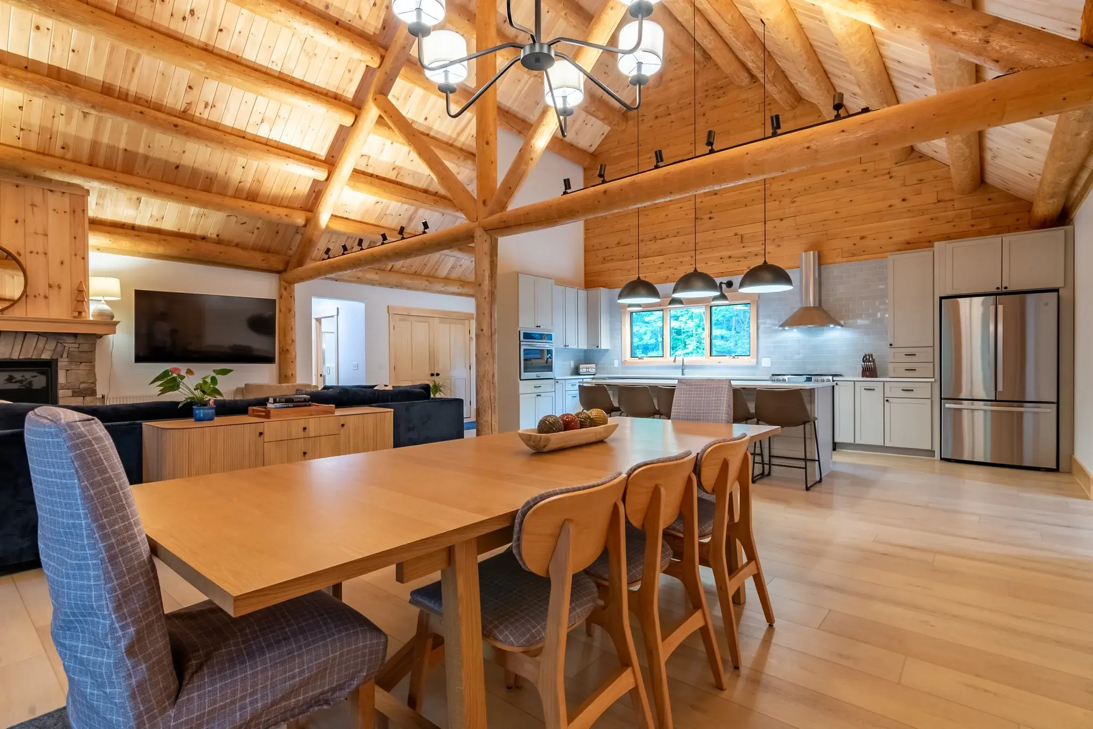 The kitchen and dining area embrace a rustic yet sophisticated design. Exposed ceiling beams set the tone, showcasing the natural charm of cedar. Clean white walls, stainless steel appliances, and simple furnishings offer a contemporary balance to th