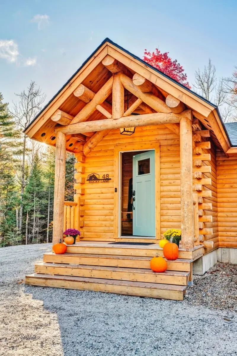 In this version of the Ashville, round log purlins and a sturdy log truss make for a warm, welcoming entry. The covered porch details like a wrought-iron lantern and cheerful teal door add to the rustic, friendly feel of this home.  