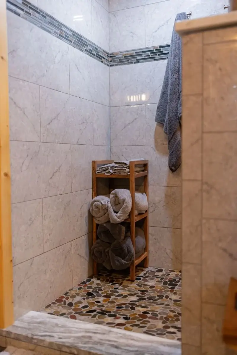 A spacious walk-in shower room combines a variety of natural stone tiles, echoing the surrounding landscape. 