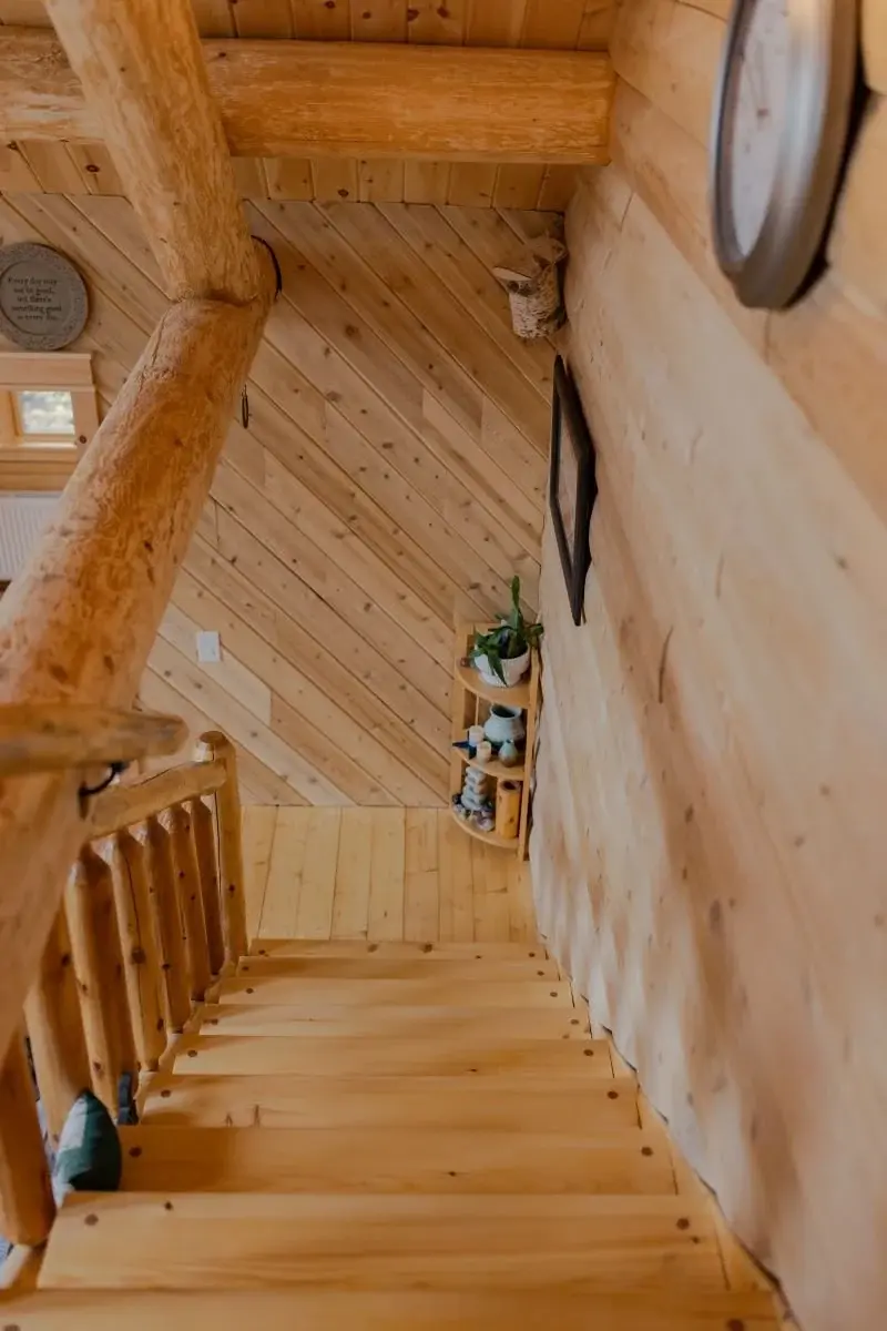 The staircase from the top story offers a great view of the exposed log trusses. 
