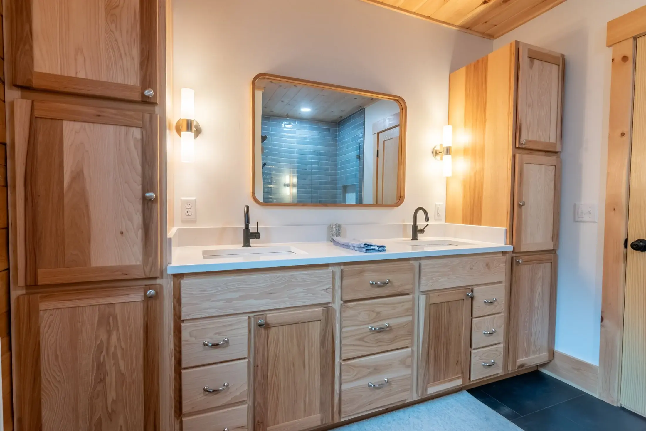 Brimming with storage, this bathroom’s practical layout and generous cabinetry make it easy to stay organized. Wall-mounted sconces flank the mirror with flattering light, while the wide-set sinks leave plenty of counter space. 