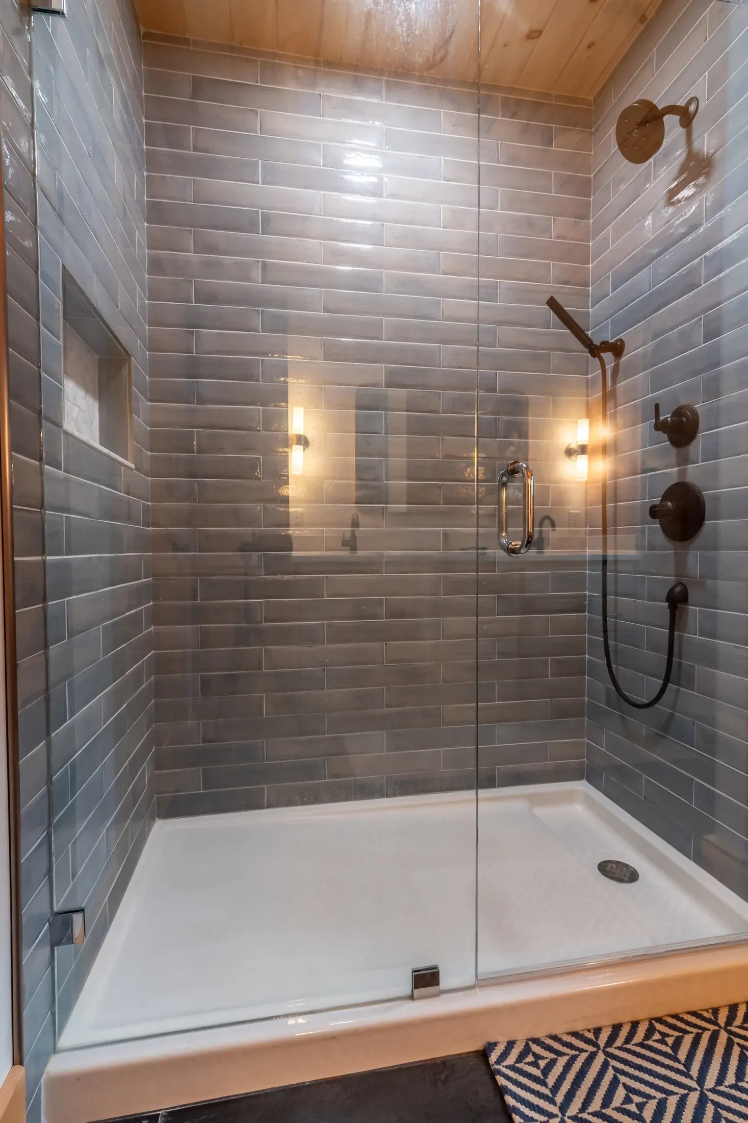 Classic subway tiles in a natural stone gray add to the timeless appeal in the walk-in shower. Upgrades like a handheld shower head and a built in niche are a few of the special touches that can really elevate a home. 
