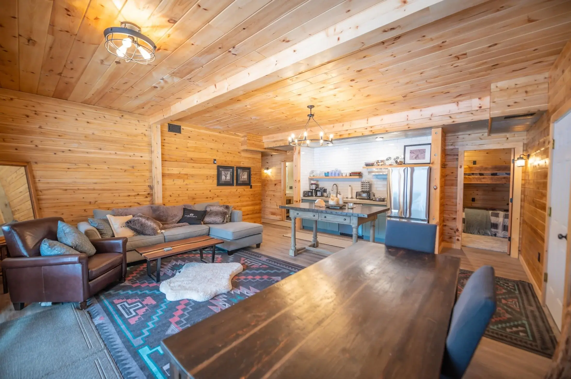 With two bedrooms, a bathroom, living room, and well-appointed kitchenette, the ground floor has all the elements of an ideal guest space. This mini great room echoes the larger space above, complete with a matching chandelier, cabinetry, and western