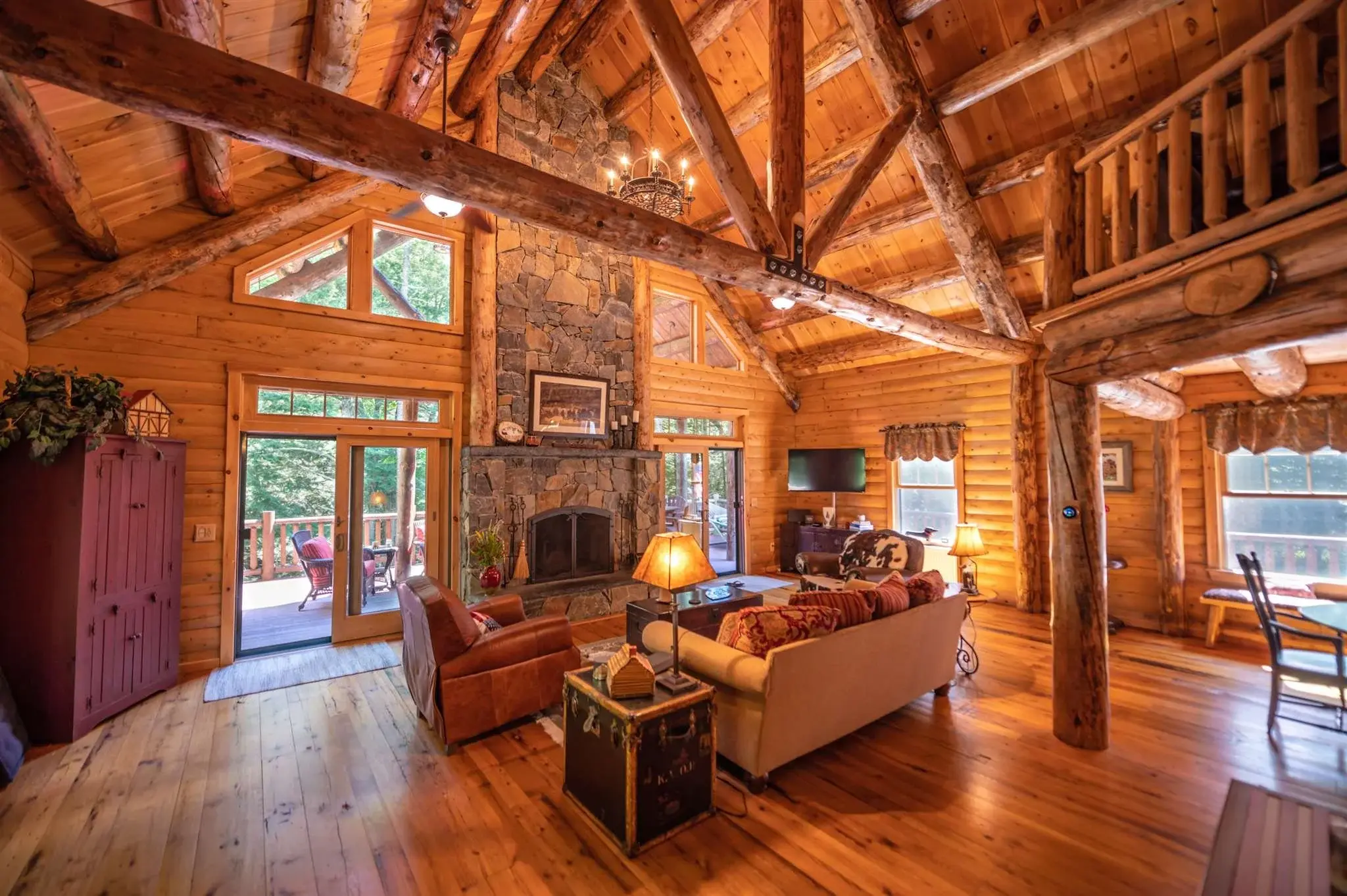 Exposed trusses with massive cedar logs are the perfect complement to the soaring fireplace in the main living room. Sliding glass doors access the deck and allow in plenty of natural light. 