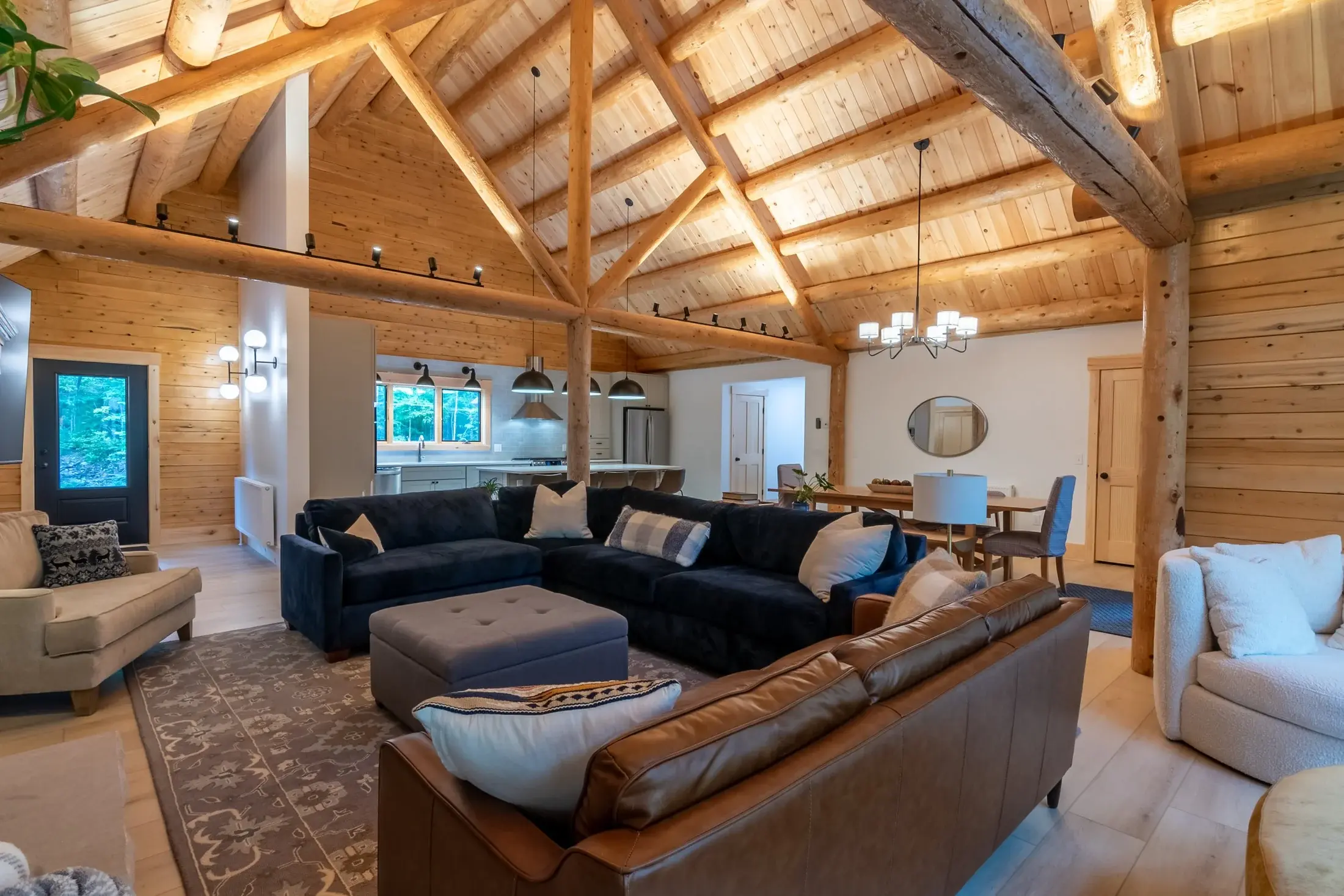 The great room embodies the perfect blend of rustic charm and modern elegance. The vaulted cedar log ceiling with exposed beams and solid round trusses makes for a commanding space, with a comfortable sitting area in warm tones adding a grounding sof