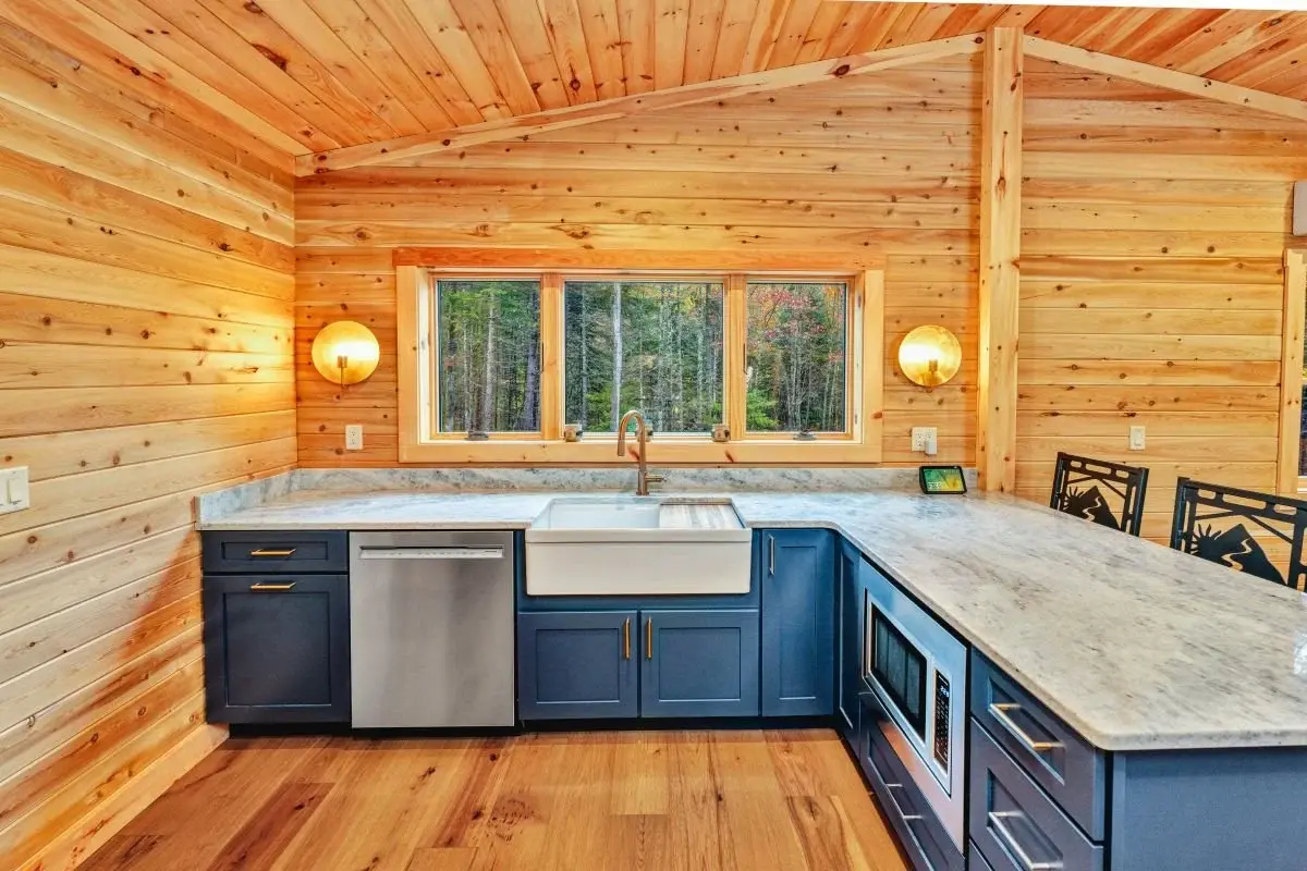 The simple L-shaped bar makes meal prep a breeze. The soft denim blue cabinets break up the warm wood tones, and keeping the countertop a simple neutral gray ties it all together. The large apron-front sink and simple cabinet hardware are both functi