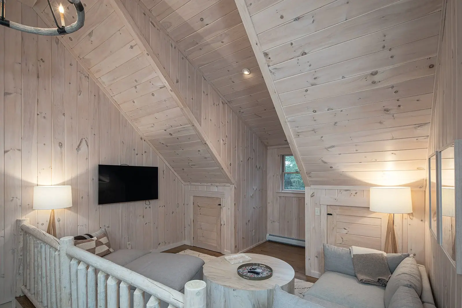 A cozy sitting area is tucked away in the loft, making the most of the square footage. Pickled white boards combined with soft furnishings in light neutral tones feel spacious and bright.