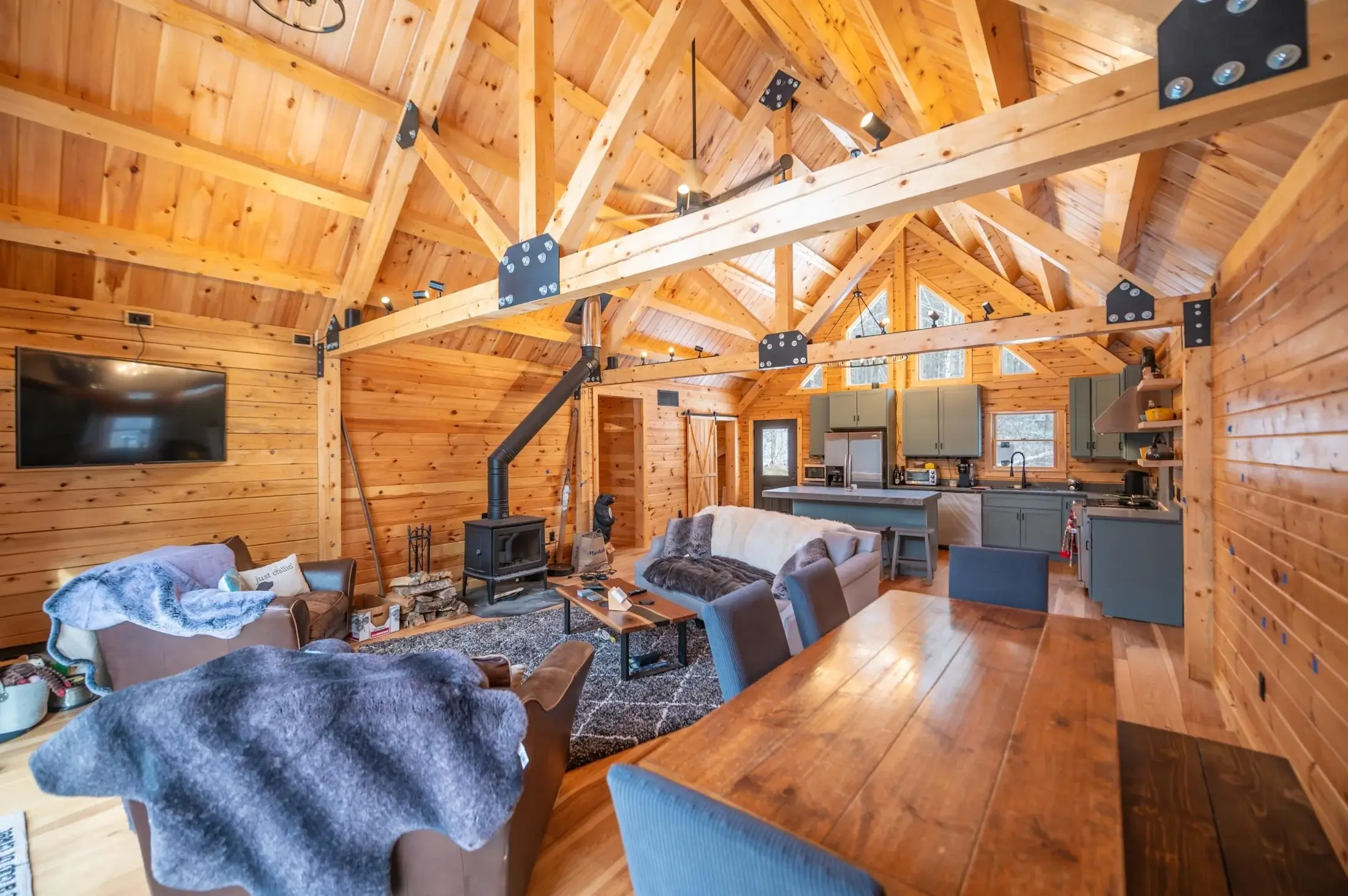 The great room features impressive cathedral ceilings with exposed square trusses, detailed with matte black plating for an industrial touch. This sturdy framing is anchored by plush, casual furnishings for a beautiful balance of comfort and durabili