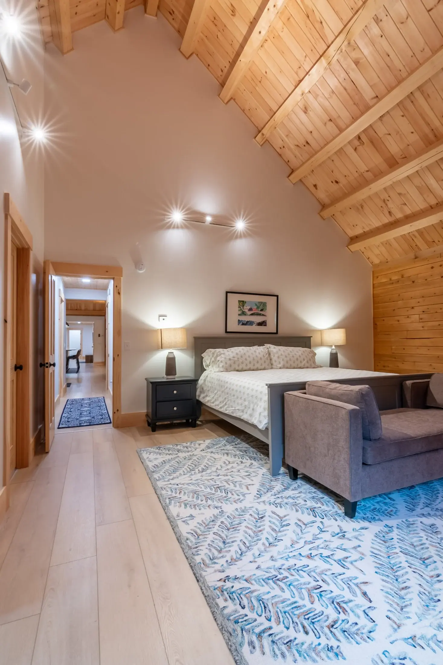 The primary bedroom feels restful with shades of blue and gray, but the abundance of light, patterned rug, and soaring cathedral ceiling add a bright and cheerful balance. 