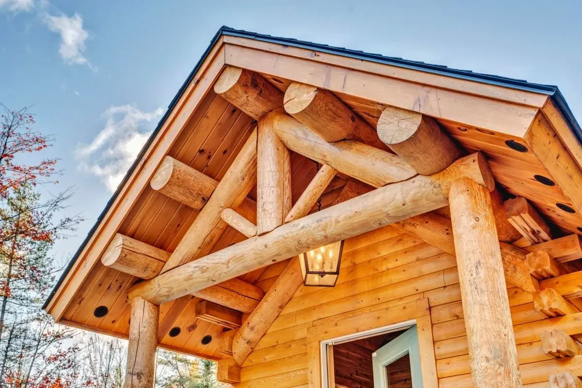 Round cedar log trusses and purlins combined with a lantern pendant light make the entrance feel sturdy, cozy, and welcoming.