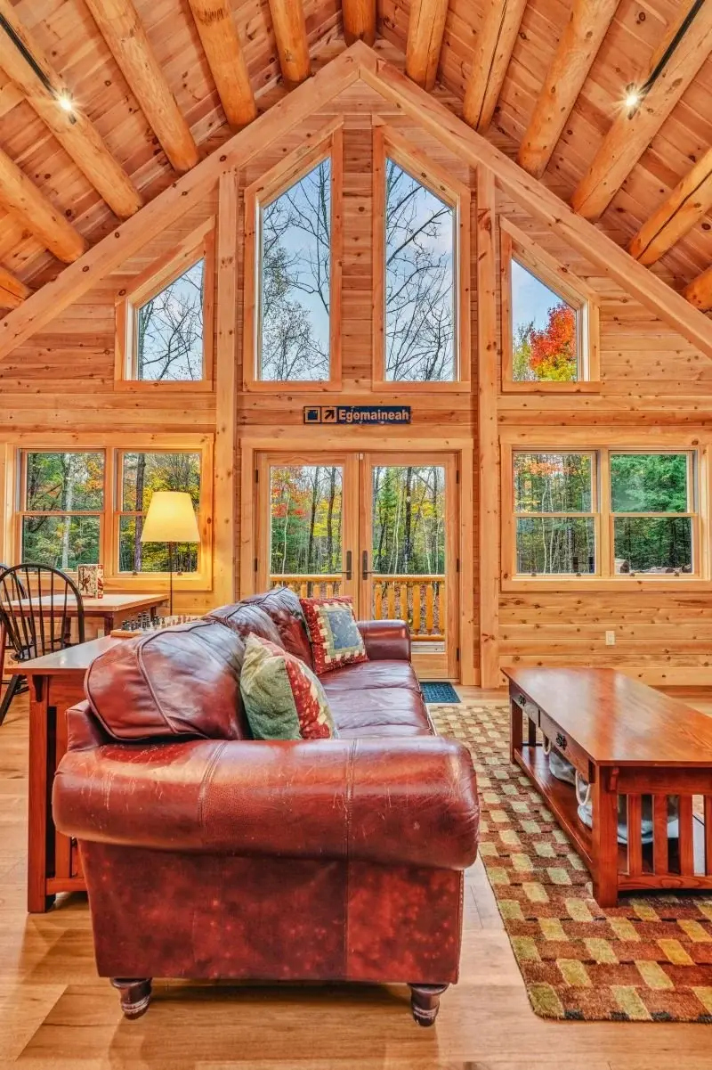 Floor to ceiling windows take in the forest views by day, while understated track lighting offers a soft glow when the sun goes down. The warm cedar tones complement the wooded landscape beyond the deck. 
