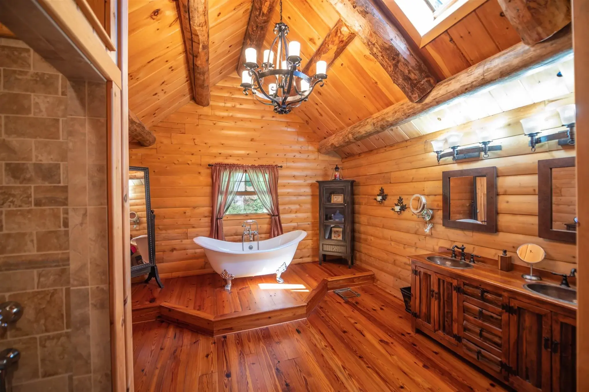 Continuing the vintage feel into the primary bathroom, the elevated clawfoot tub and industrial chandelier make a bold statement. 