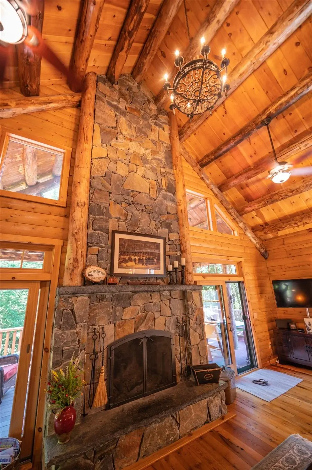 Spanning two stories, this grand fieldstone fireplace is artfully paired with a bold chandelier and flanked by log posts to ensure it fits the scale of the home. 