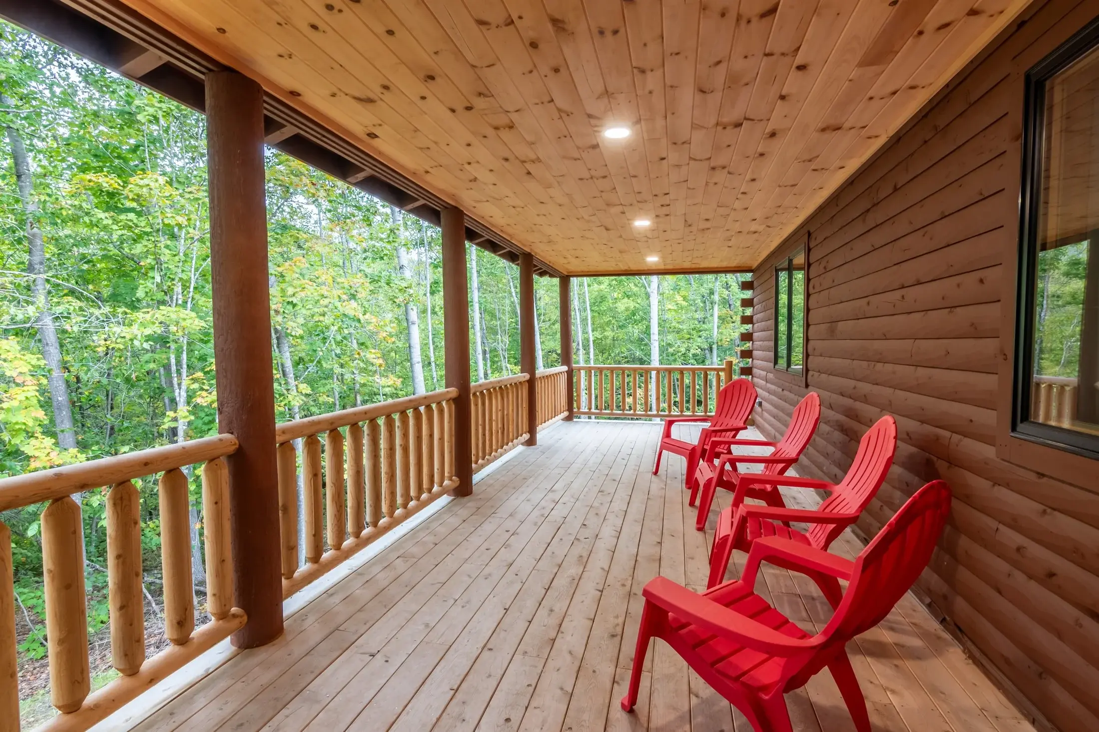 The covered porch off the great room naturally blends deep earthy browns and light, fresh cedar tones for a true reflection of the forest beyond. Recessed lighting and comfortable Adirondack chairs invite outdoor relaxation any time of day or night. 