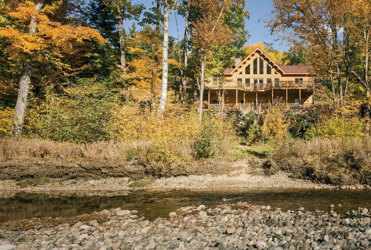 Exterior of multi level log home alongside the creek