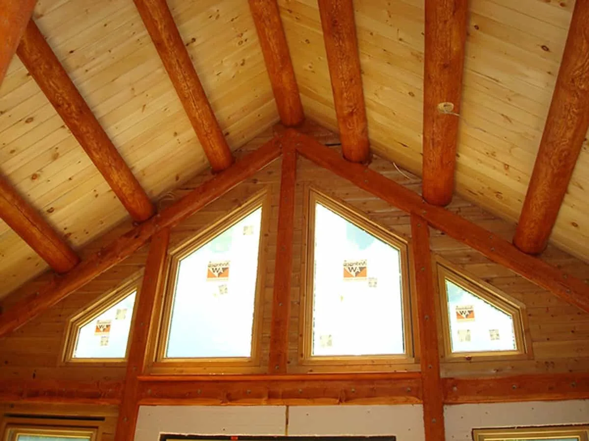 Exposed wooden ceiling beams made from whole logs give this cabin a handmade look.